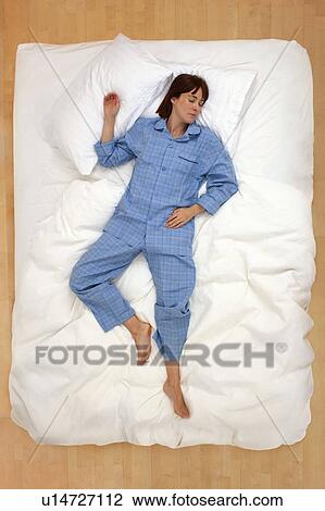 Stock Image - Woman lying in bed, asleep. Fotosearch