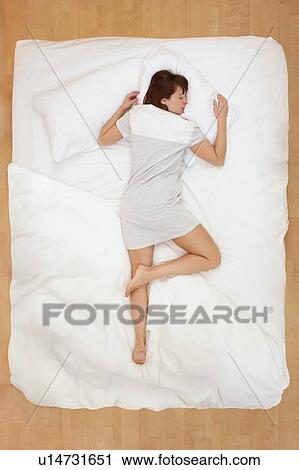 Stock Image - Woman lying in bed, asleep. Fotosearch