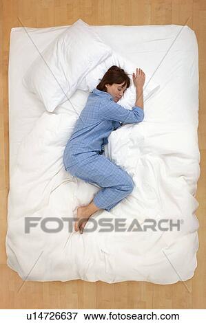 Stock Photo - Woman lying in bed, asleep. Fotosearch