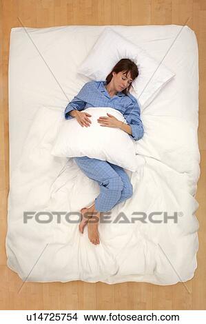 Woman lying in bed holding pillow View Large Photo Image Picture - Woman lying in bed holding pillow. Fotosearch