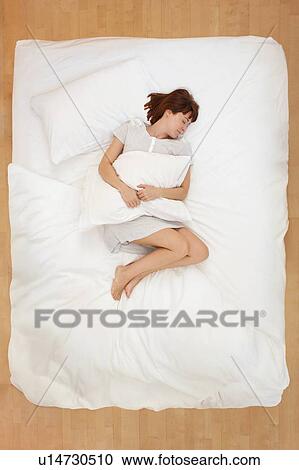 Woman lying in bed holding pillow View Large Photo Image Stock Image - Woman lying in bed holding pillow. Fotosearch