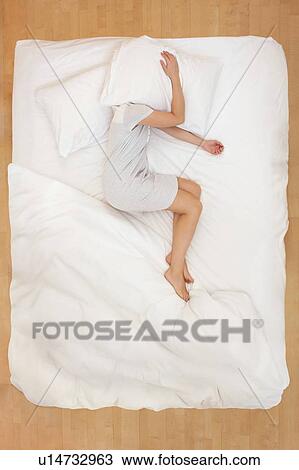 Woman lying in bed with pillow over head View Large Photo Image Stock Image - Woman lying in bed with pillow over head. Fotosearch