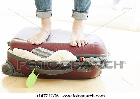 Woman packing, standing on full suitcase View Large Photo Image Stock Photograph - Woman packing, standing on full suitcase. Fotosearch
