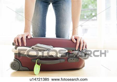 Woman pushing down on full suitcase View Large Photo Image Stock Photography - Woman pushing down on full suitcase. Fotosearch