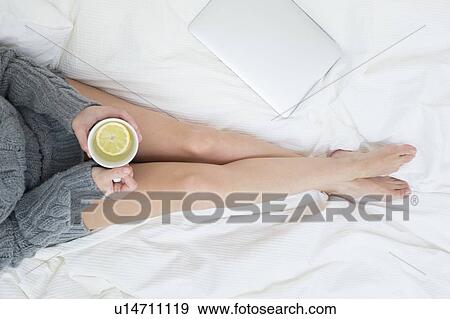 Woman sitting on bed with cup View Large Photo Image Stock Photo - Woman sitting on bed with cup. Fotosearch