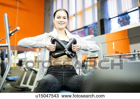 Stock Image - Woman using rowing machine. Fotosearch
