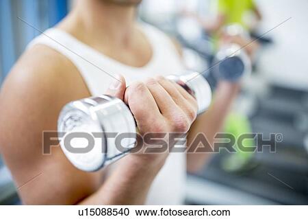 Young man holding dumbbells, close-up View Large Photo Image Stock Image - Young man holding dumbbells, close-up. Fotosearch