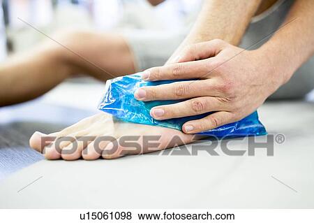 Young man holding ice pack on ankle View Large Photo Image Stock Photo - Young man holding ice pack on ankle. Fotosearch