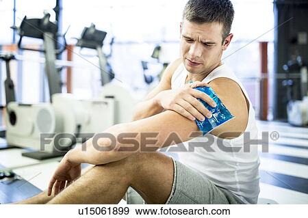 Stock Photo - Young man holding ice pack on shoulder. Fotosearch