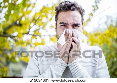 Stock Image - Young man sneezing. Fotosearch