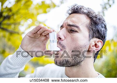 Stock Photo - Young man using inhaler. Fotosearch