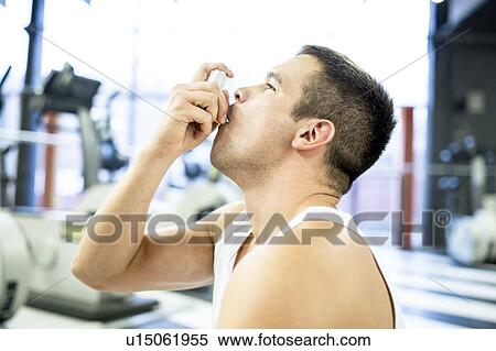 Stock Photography - Young man using inhaler. Fotosearch