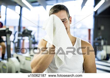 Stock Photo - Young man wiping his sweat with towel. Fotosearch