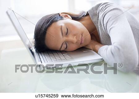Stock Photo - Young woman asleep on laptop. Fotosearch