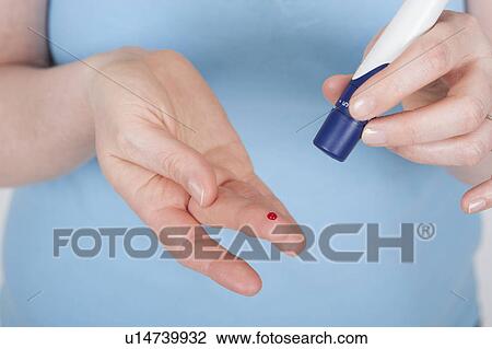Stock Image - Young woman doing a finger prick test. Fotosearch