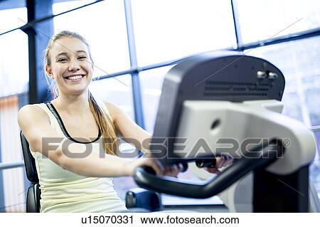 Young woman exercising on exercise bike View Large Photo Image Stock Image - Young woman exercising on exercise bike. Fotosearch