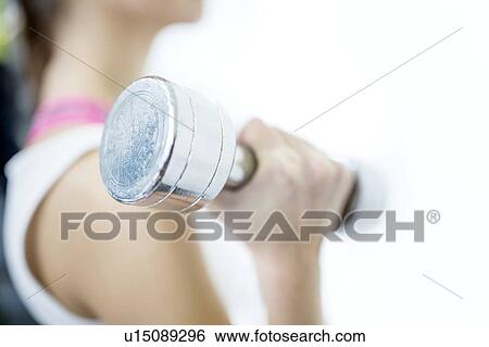 Stock Photograph - Young woman holding dumbbell, close-up. Fotosearch