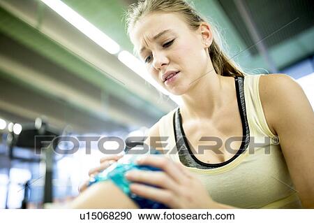 Young woman holding ice pack on knee View Large Photo Image Stock Image - Young woman holding ice pack on knee. Fotosearch