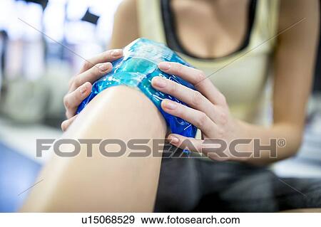 Young woman holding ice pack on knee View Large Photo Image Stock Photo - Young woman holding ice pack on knee. Fotosearch