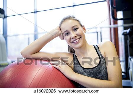 Stock Photograph - Young woman leaning on fitness ball. Fotosearch