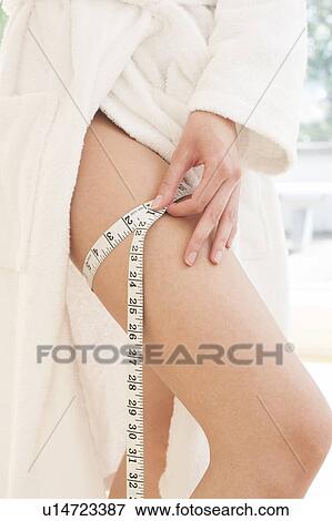 Stock Photo - Young woman measuring thigh. Fotosearch