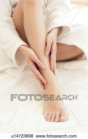 Stock Photo - Young woman rubbing ankle. Fotosearch