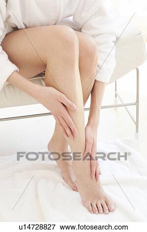 Stock Photo - Young woman rubbing leg and ankle. Fotosearch