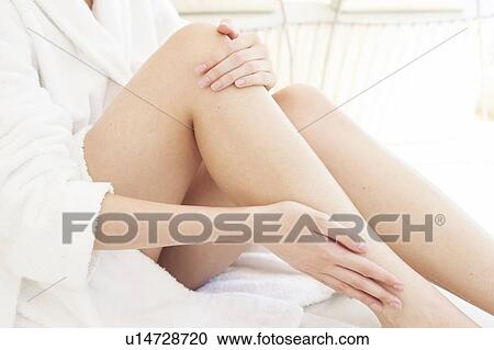 Stock Image - Young woman rubbing leg. Fotosearch