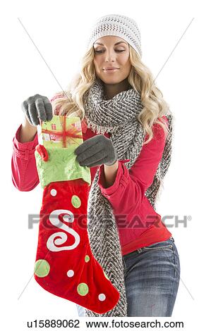 Stock Image - Young woman taking out present from Christmas stocking. Fotosearch