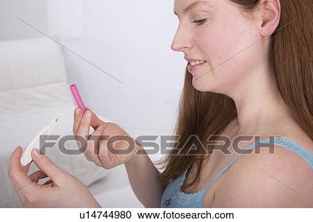 Stock Image - Young woman taking pregnancy test at home. Fotosearch