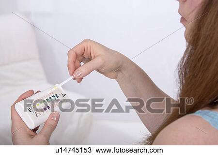 Stock Image - Young woman testing urine sample. Fotosearch