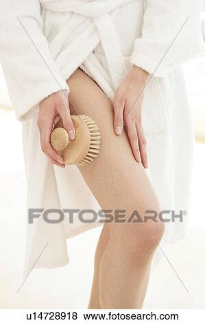 Stock Photo - Young woman using body brush on leg. Fotosearch