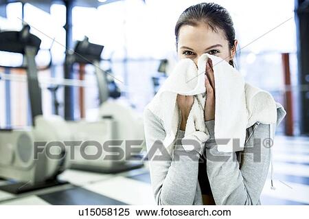 Stock Photography - Young woman wiping her face, portrait. Fotosearch