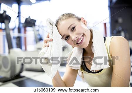 Young woman wiping her sweat with towel View Large Photo Image Stock Photo - Young woman wiping her sweat with towel. Fotosearch