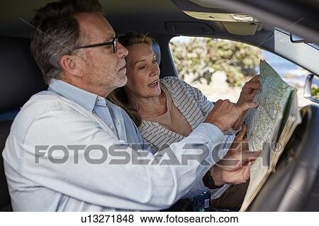 Couple in car reading a map View Large Photo Image Stock Photo - Couple in car reading a map. Fotosearch