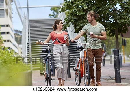 Couple walking with bikes View Large Photo Image Picture - Couple walking with bikes. Fotosearch