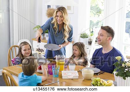 Stock Photograph - Family at dining table having a meal. Fotosearch