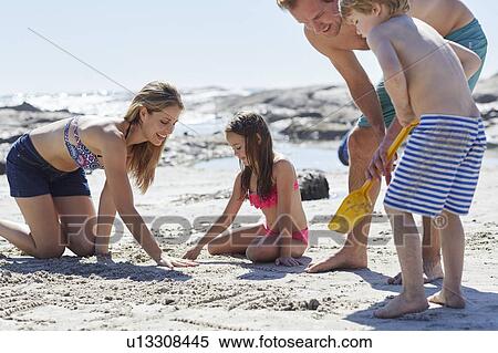 Stock Photography - Family playing on beach. Fotosearch