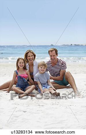 Picture - Family sitting on beach. Fotosearch