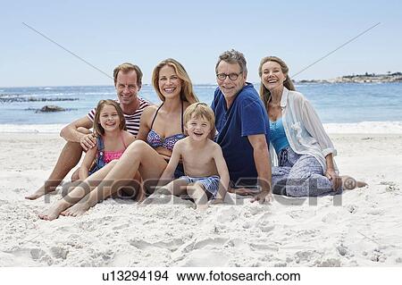 Picture - Family sitting on beach. Fotosearch