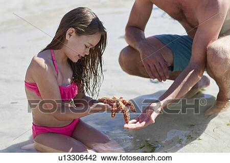 Father and daughter holding starfish View Large Photo Image Stock Image - Father and daughter holding starfish. Fotosearch