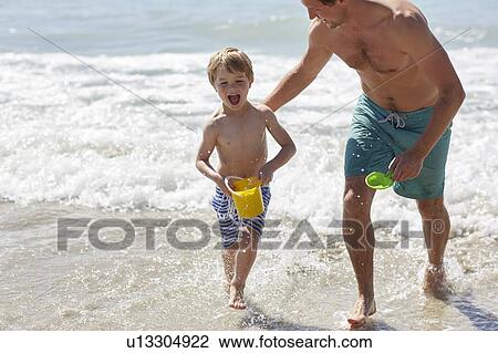 Stock Image - Father and son playing on beach. Fotosearch
