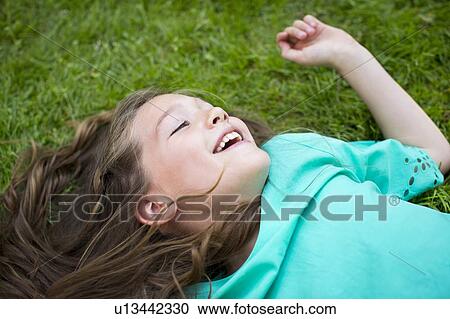 Stock Image - Girl lying on the grass, smiling. Fotosearch