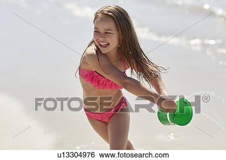 Girl playing on beach with bucket View Large Photo Image Stock Photograph - Girl playing on beach with bucket. Fotosearch