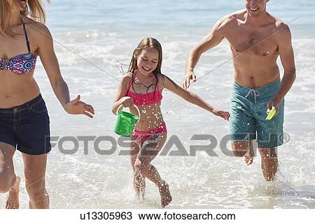 Girl playing on beach with her parents View Large Photo Image Stock Image - Girl playing on beach with her parents. Fotosearch