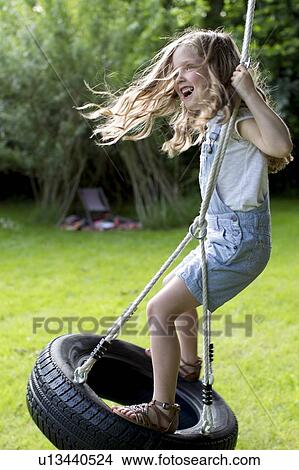 Picture - Girl playing on tyer swing. Fotosearch