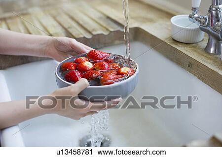 Stock Image - Girl washing fresh strawberries. Fotosearch