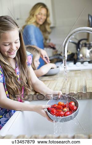 Stock Photo - Girl washing fresh strawberries. Fotosearch