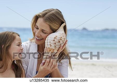 Stock Photography - Mother and daughter with seashell. Fotosearch