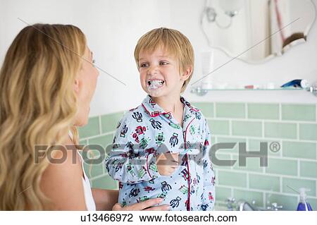 Stock Image - Mother and son in bathroom brushing teeth. Fotosearch